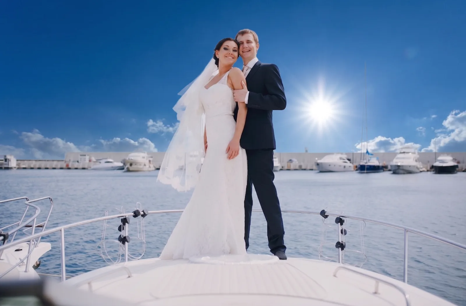 Newlywed couple posing on the bow of a yacht